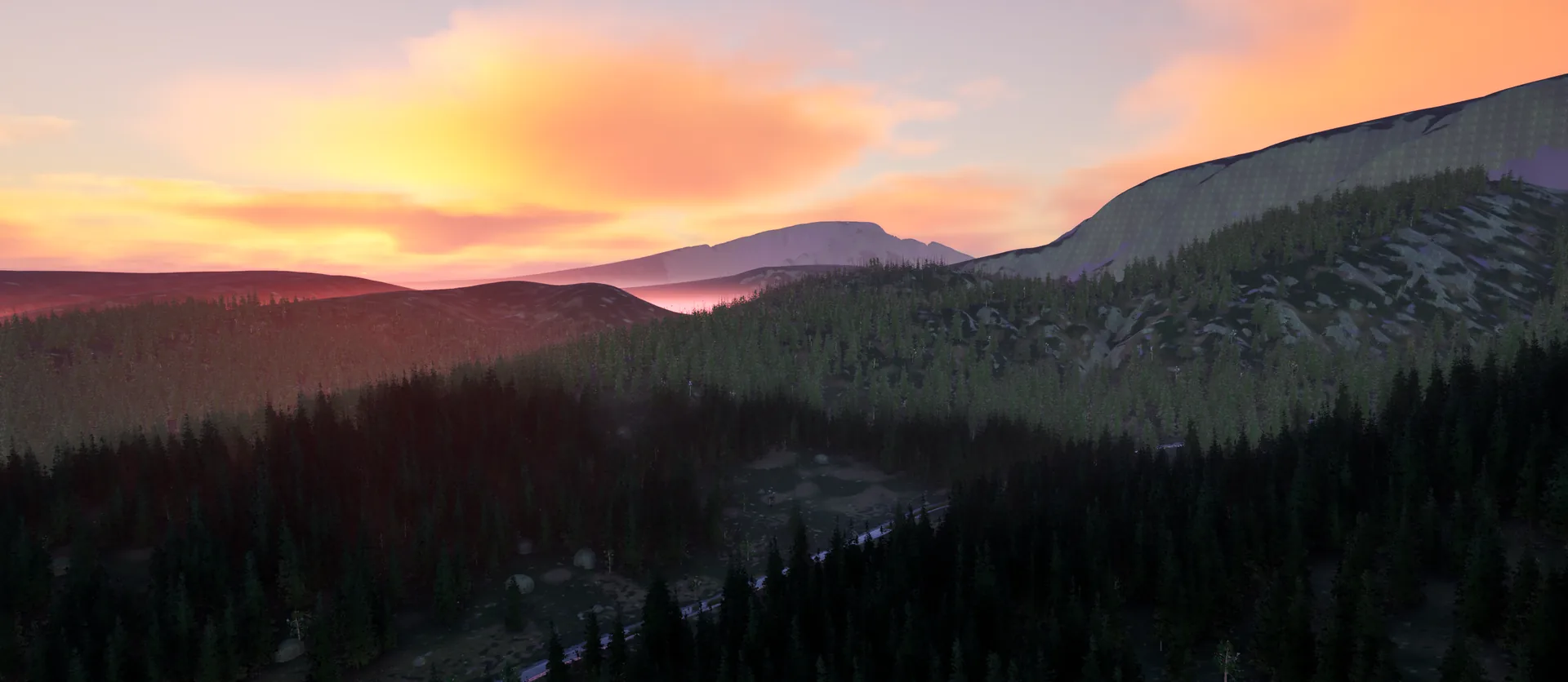 Sunset over forested hills, the sky glowing orange and pink above a bare mountain