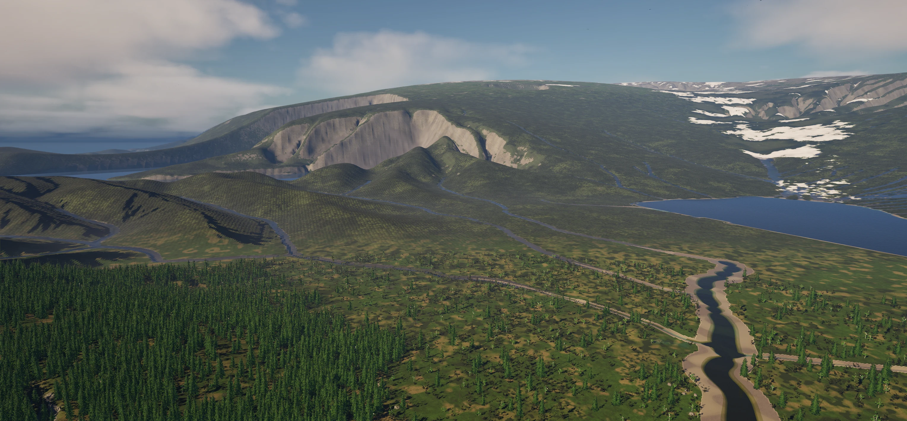 Aerial view of the green valley floor below the mountain lake, with a winding river, dark spruce forest on the left, and steep rocky cirque walls in the background